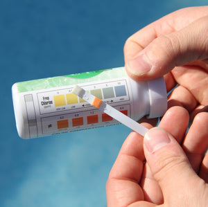 <On a blue sky and wispy cloud background, an analyst checking a pH test strip with a colour chart to determine the orange colour is equivalent to pH 6.8. Credit> AdobeStock_201253305