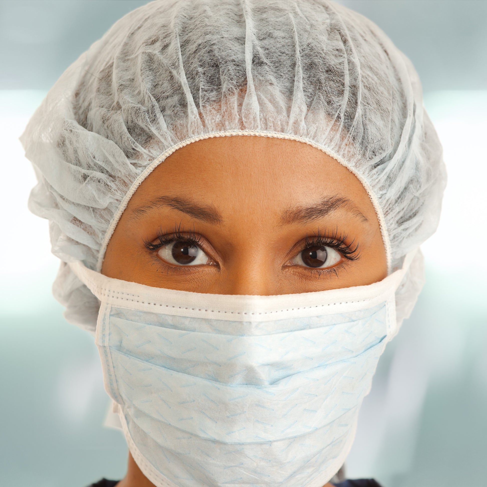 <Close up of female employee's face wearing a white hairnet and face mask. Credit> AdobeStock_223463107