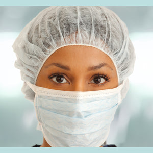 <Female production operator with brown eyes and skin demonstrating the correct way to wear a white hairnet and face mask as per the gowning procedure. Credit> AdobeStock_223463107