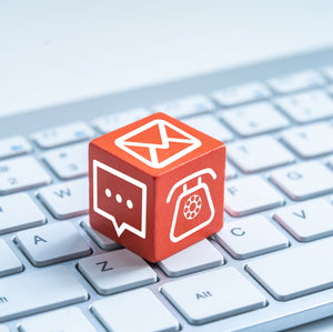 <Red cube with emergency e-mail, letter, and phone symbols on the three visible faces, sitting on a white laptop keyboard. Credit> AdobeStock_277649030