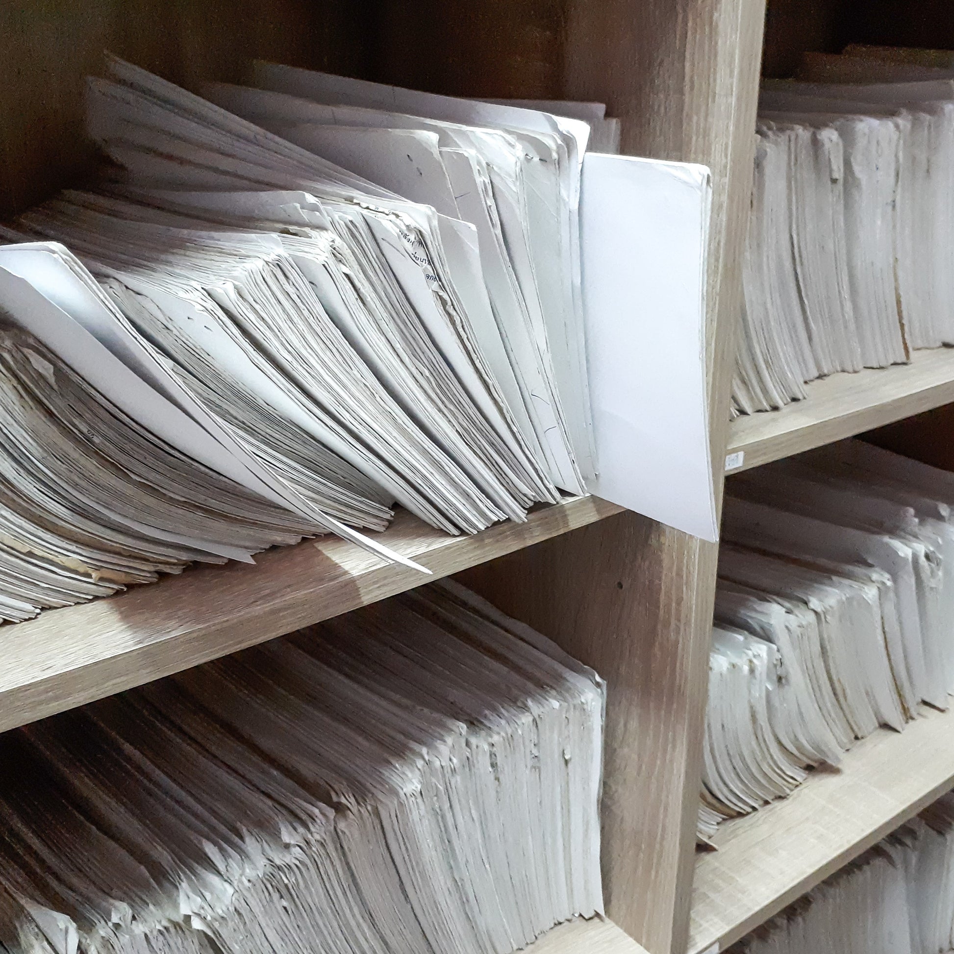 <Two wooden shelf units full of paper GMP records stored in booklets. Credit> AdobeStock_293074565