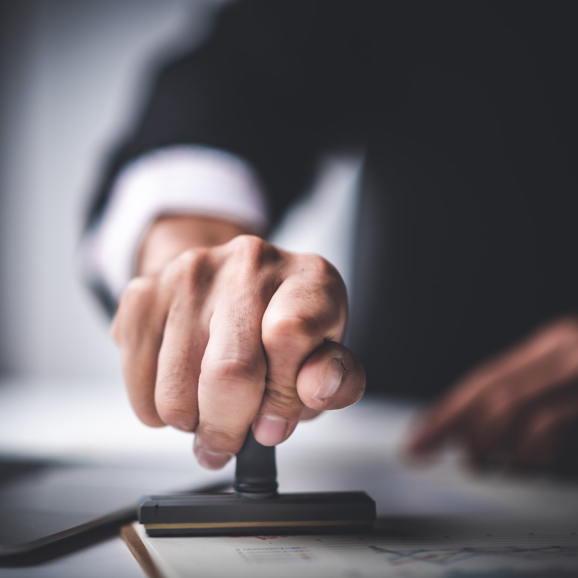 <Man in suit making a disposition decision on a batch of materials with an ink stamp. Credit> AdobeStock_295934749