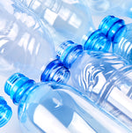 <Two rows of clear, blue plastic bottles lying down in opposite directions top next to top. Credit> AdobeStock_297593696