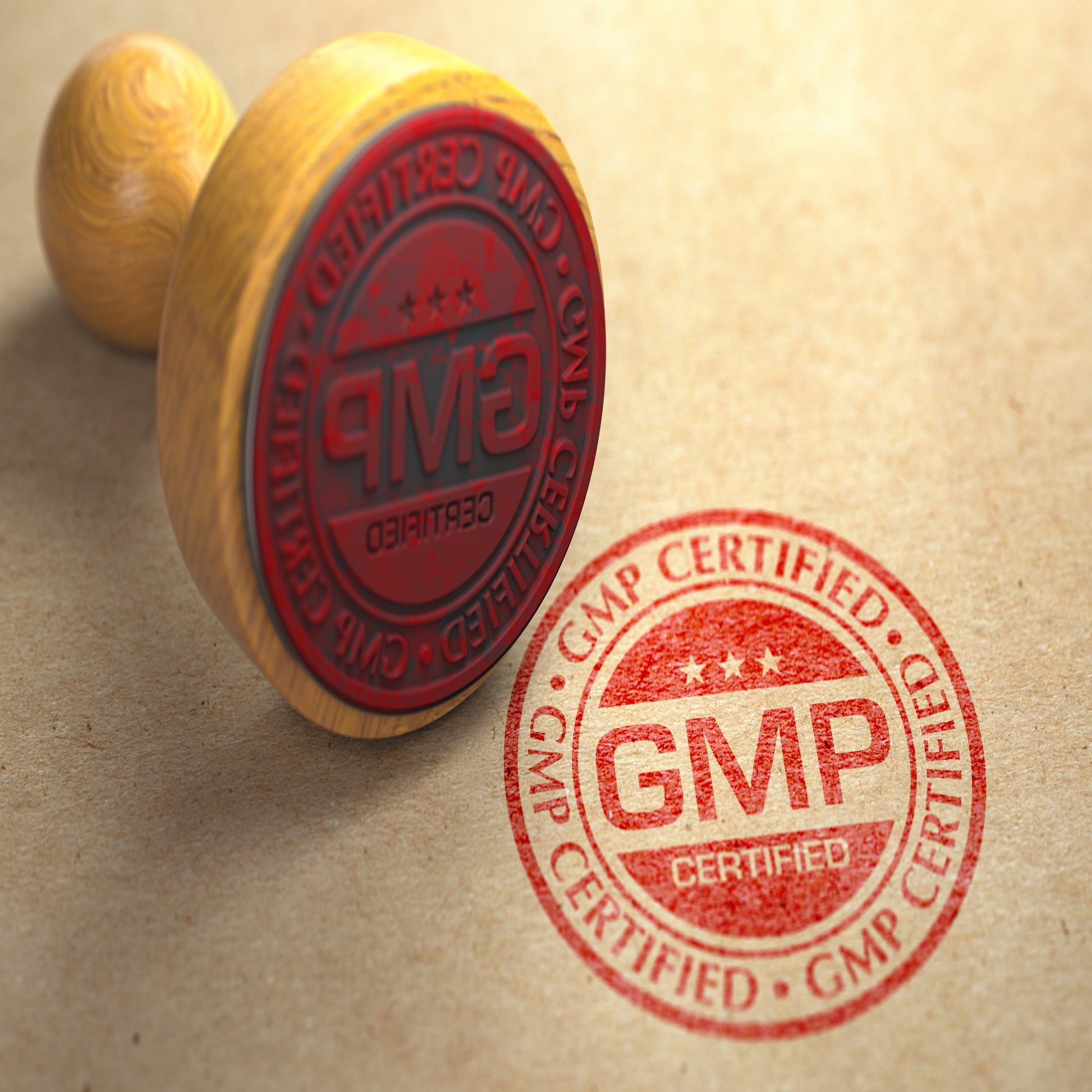 <Pale wooden hand stamp lying on its side having used red ink to stamp GMP Certified as a red, round logo with 3 stars on a cream stone effect surface. Credit> AdobeStock_413551778_1