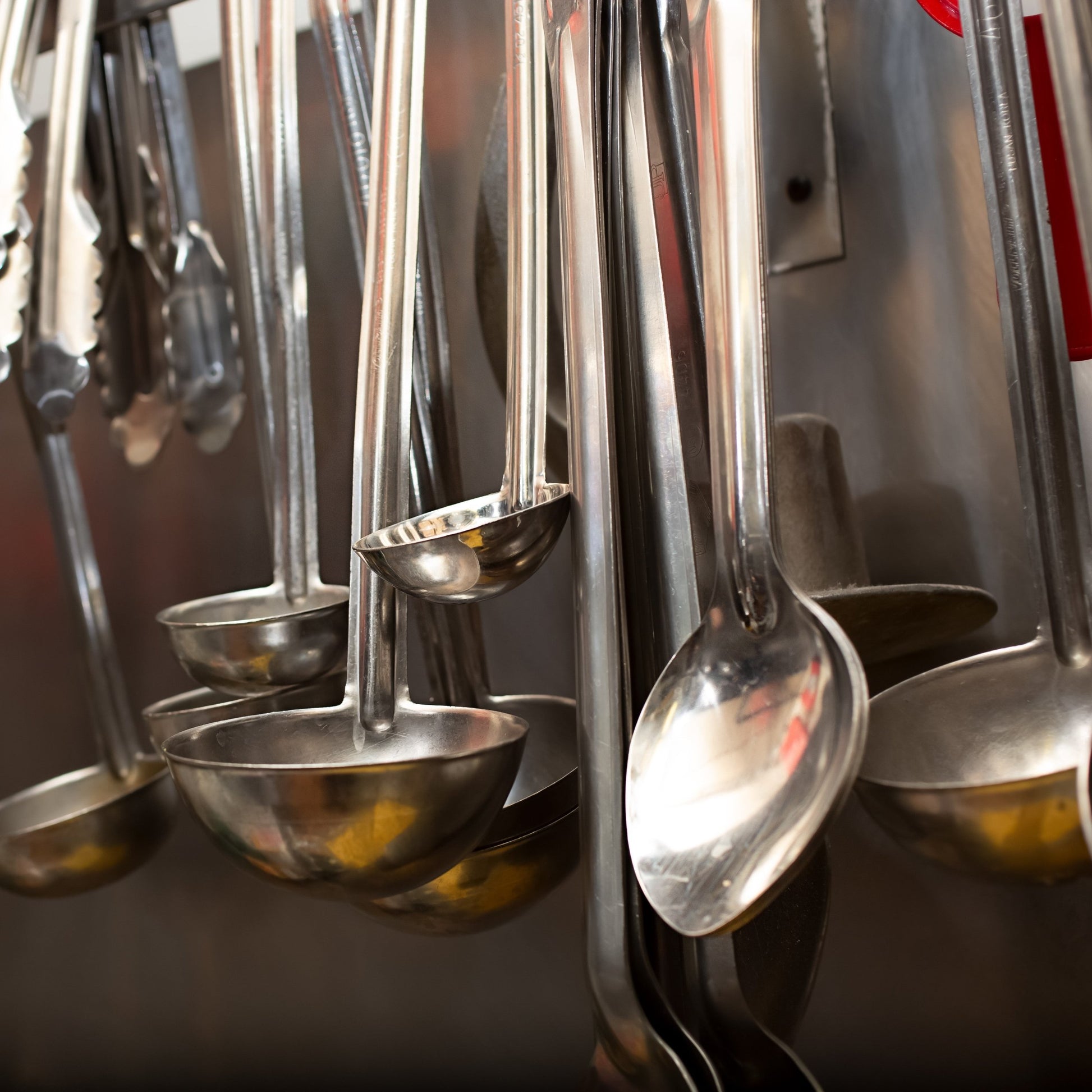 <Cleaned stainless steel utensils such as spoons, ladels and stirrers, used to manufacture dietary supplements hanging on a rack to dry. Credit> AdobeStock_417273659