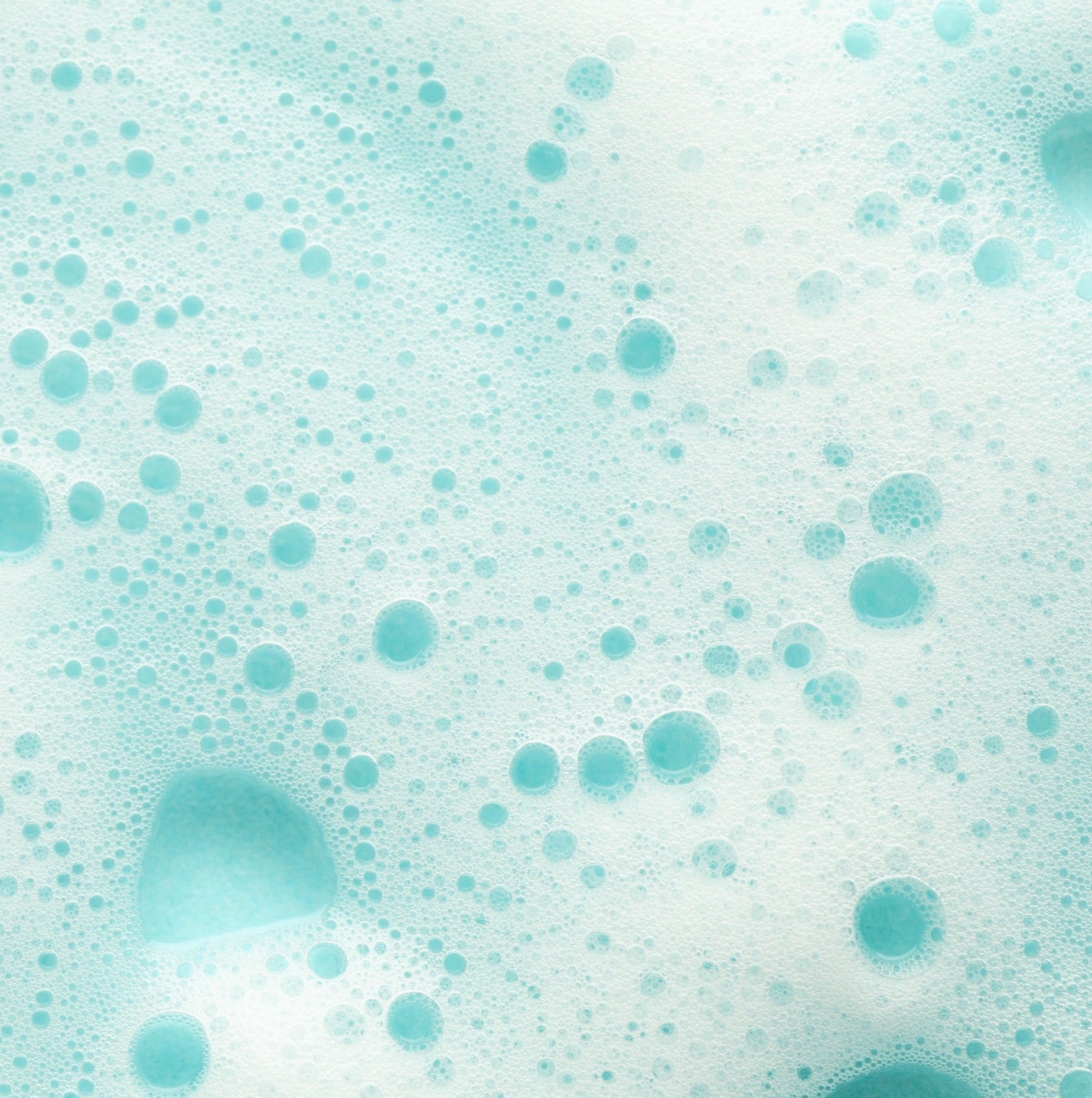 <Close up picture of white foam bubbles on top of water in a light blue container. Credit> AdobeStock_484934288