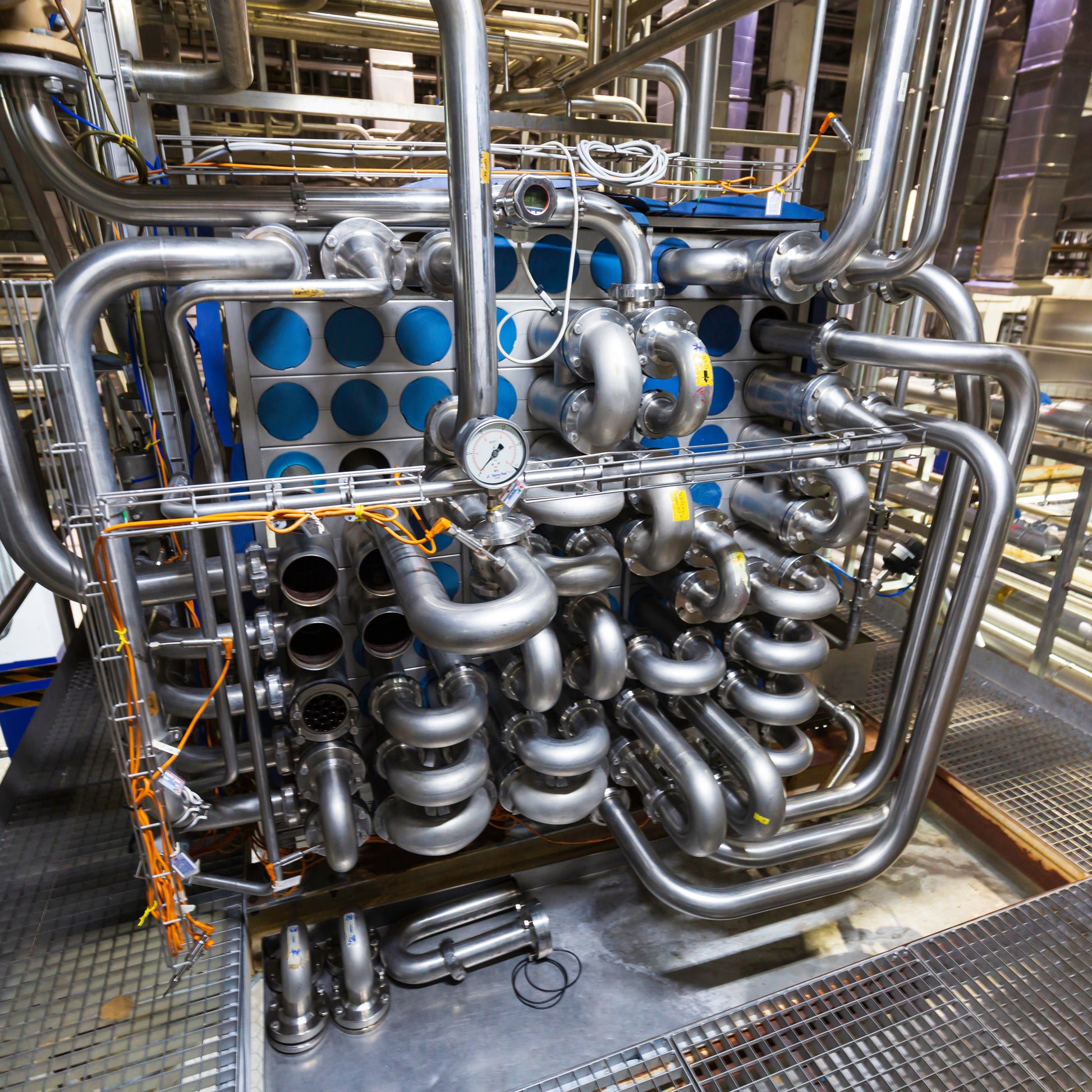 <Industrial heat exchanger made up of coils of stainless steel pipes in a cube with pressure gauge for fast heating purified water for a drug manufacturing area. Credit> AdobeStock_527336253