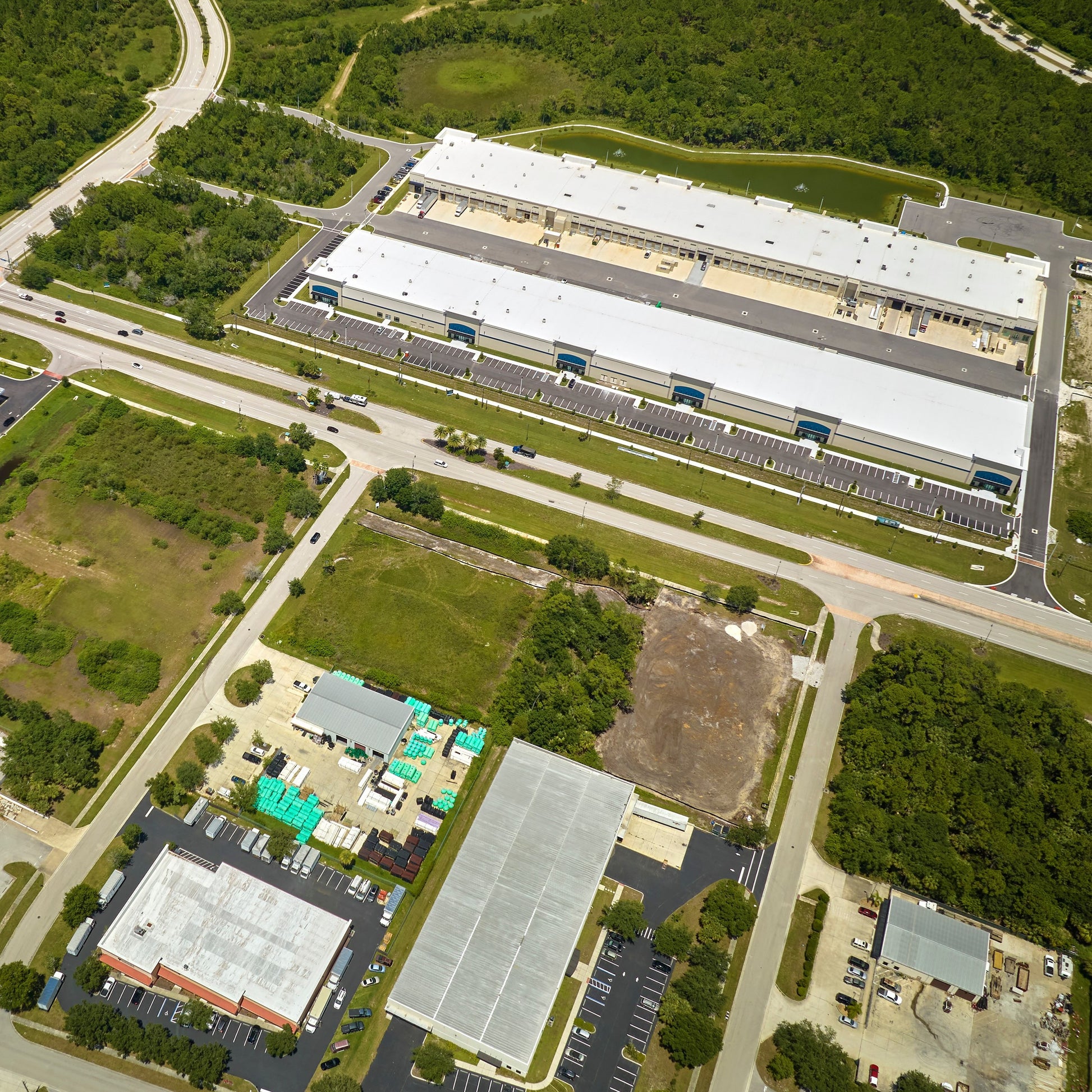 <Overhead photograph of a dietary supplement facility with several buildings, yards, roads, parking lots, and green areas. Credit> AdobeStock_632812255