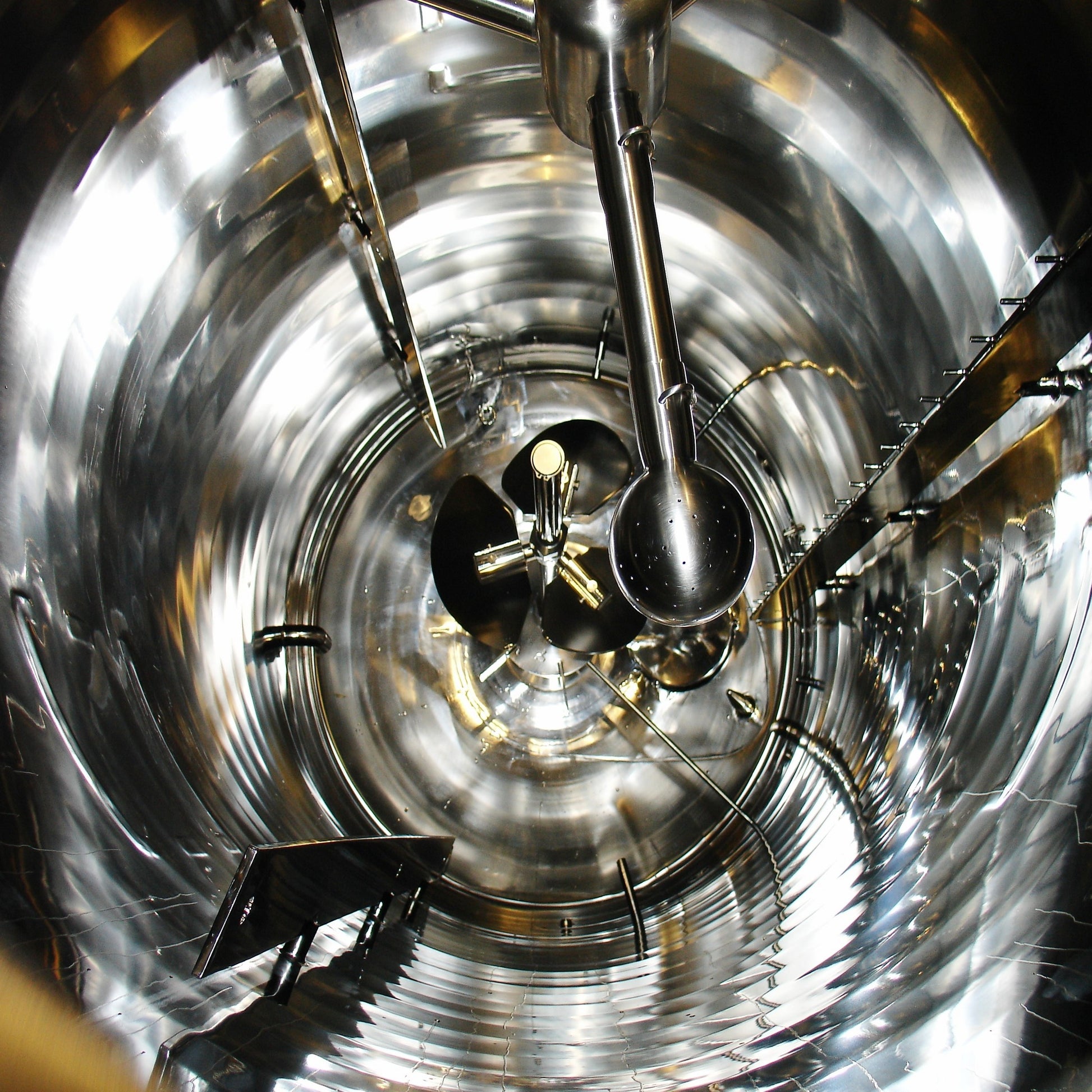 <Looking down inside a cylindrical polished stainess steel mixing tank used to manufacture dietary supplements, with propellor stirrer, agitator, and baffles, that has just been cleaned and sanitized. Credit> Fotoluca@Freeimages#1185019