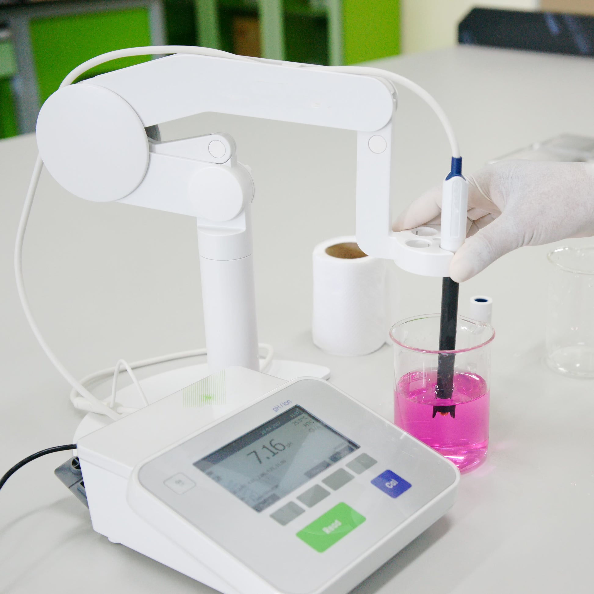 <White combined digital pH and Conductivity meter on a white lab surface with black probe immersed in a purple clear liquid in a beaker, possibly buffer solution. Credit>  95223342 © Puntasit Choksawatdikorn | Dreamstime.com 