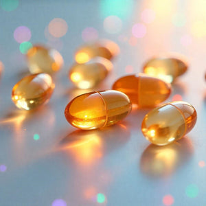 <The liquid in clear amber coloured gel capsules lying on a white worktop refracting sunlight and creating orange, blue and pink light effects. Credit> Freepik