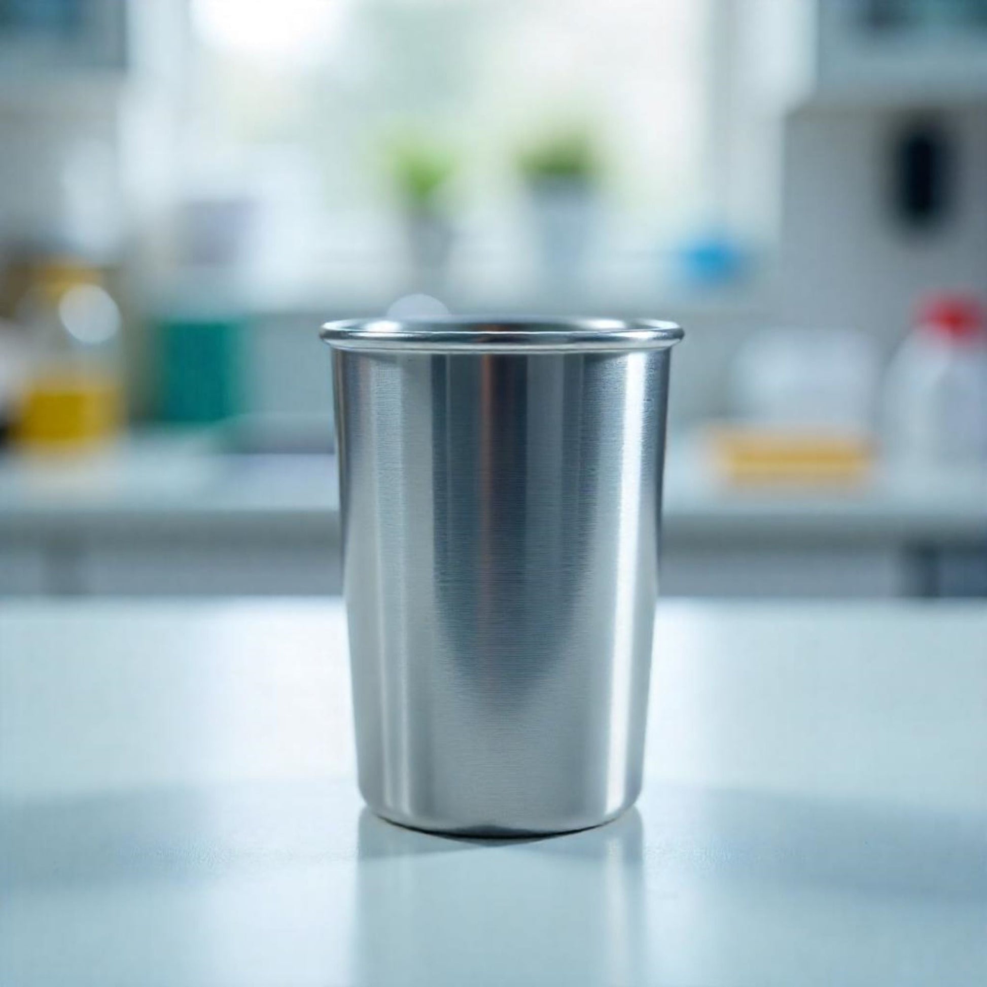 <Straight sided stainless steel pycnometer cup on a white lab worktop and blurred laboratory background. Credit> Freepik